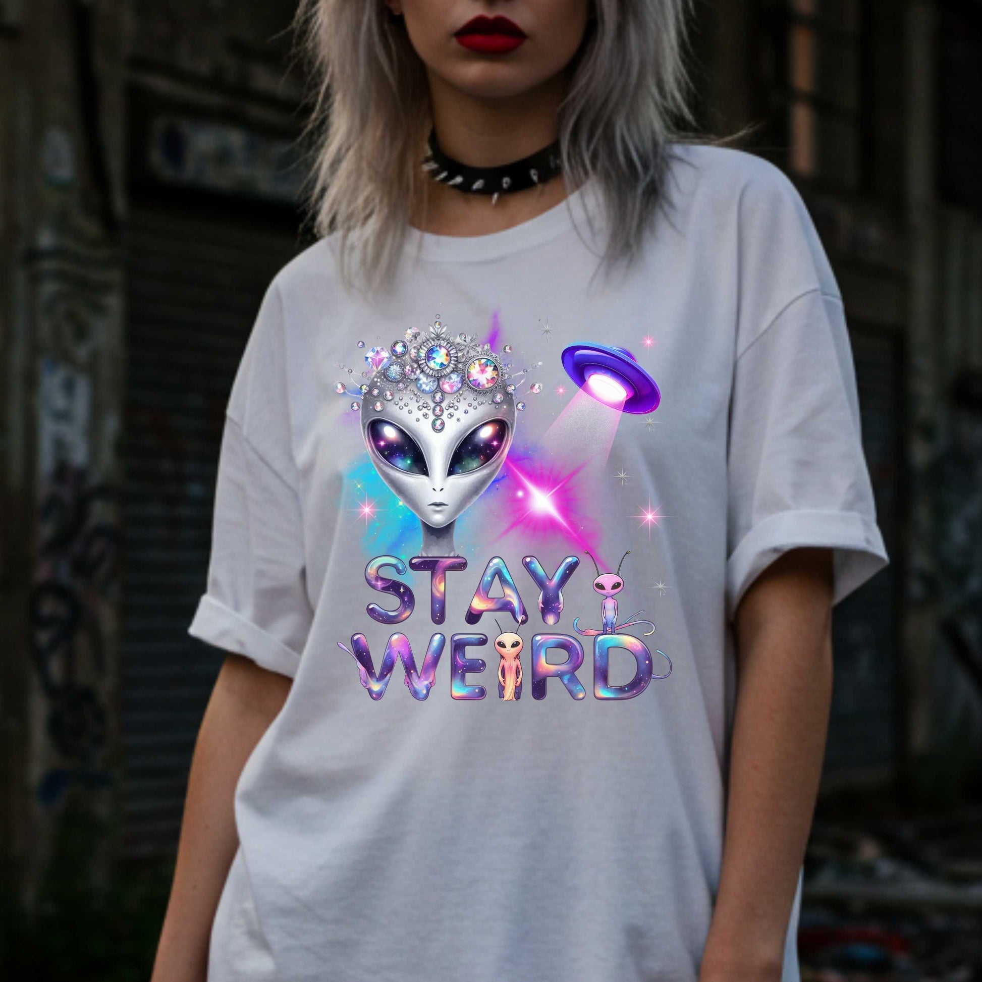 Beam us up, queen—the galaxy’s weirdest and most fabulous fashion icon has entered the orbit. This Stay Weird alien graphic tee is here to remind Earthlings that normal is overrated. Featuring a cosmic glam alien with jeweled headgear and a full-on abduction spotlight moment, this shirt is serving interstellar weirdness with a side of sparkle. 
