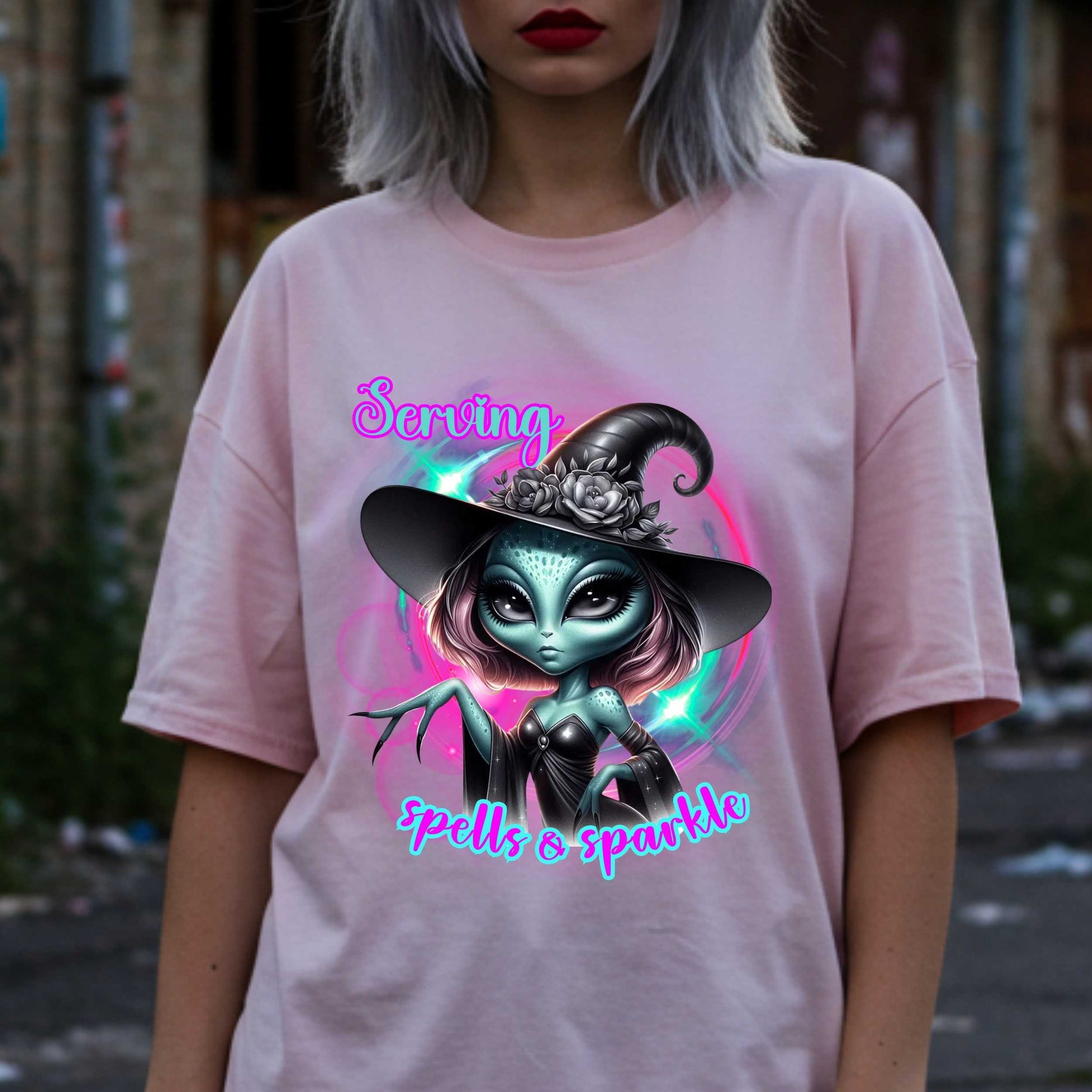Serving intergalactic glam with a side of sparkle and sass! This glam alien witch graphic tee is perfect for the spooky season and every day you feel too fabulous for Earth. Featuring a fierce extraterrestrial baddie in full witchy slay mode, this shirt says, “I cast spells, but I do it in highlighter and heels.”