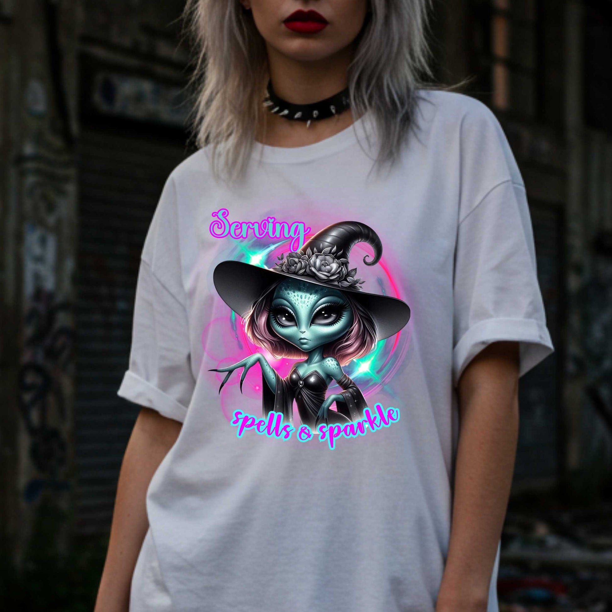 Serving intergalactic glam with a side of sparkle and sass! This glam alien witch graphic tee is perfect for the spooky season and every day you feel too fabulous for Earth. Featuring a fierce extraterrestrial baddie in full witchy slay mode, this shirt says, “I cast spells, but I do it in highlighter and heels.”