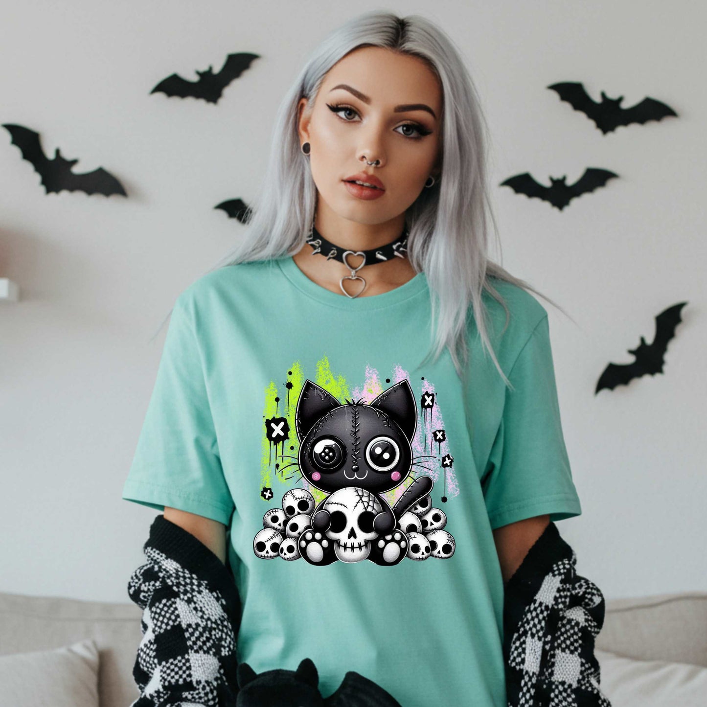 Pastel goth cat Halloween shirt for the spooky babe who wants to be cute, creepy, and slightly unbothered by your opinions. This little stitched-up kitten is sittin’ pretty on a pile of skulls, looking like she just clawed her way out of a haunted Lisa Frank binder. It’s soft, spooky, and a little sinister—just like your mood in October (and let’s be honest, year-round).&nbsp;