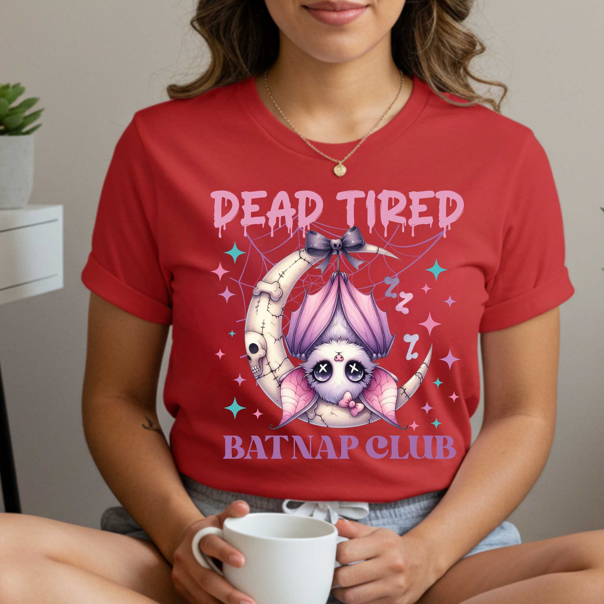 Dead tired and fully over it? Same. Join the Batnap Club with this pastel goth bat Halloween shirt, featuring a sleepy little winged gremlin who’s clearly clocked out. Wrapped in a pink bow and hanging like tomorrow’s problems, this adorable burnout bat is all of us in October (and every Monday). Perfect for spooky naps, haunted errands, or just surviving on caffeine and vibes.&nbsp;
