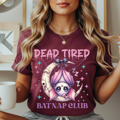 Dead tired and fully over it? Same. Join the Batnap Club with this pastel goth bat Halloween shirt, featuring a sleepy little winged gremlin who’s clearly clocked out. Wrapped in a pink bow and hanging like tomorrow’s problems, this adorable burnout bat is all of us in October (and every Monday). Perfect for spooky naps, haunted errands, or just surviving on caffeine and vibes.&nbsp;