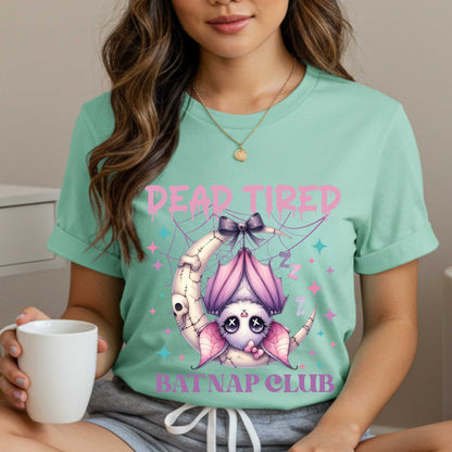 Dead tired and fully over it? Same. Join the Batnap Club with this pastel goth bat Halloween shirt, featuring a sleepy little winged gremlin who’s clearly clocked out. Wrapped in a pink bow and hanging like tomorrow’s problems, this adorable burnout bat is all of us in October (and every Monday). Perfect for spooky naps, haunted errands, or just surviving on caffeine and vibes.&nbsp;