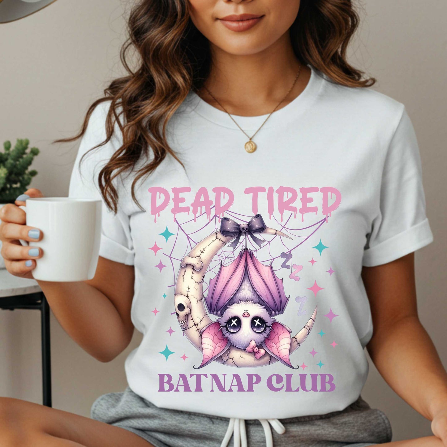 Dead tired and fully over it? Same. Join the Batnap Club with this pastel goth bat Halloween shirt, featuring a sleepy little winged gremlin who’s clearly clocked out. Wrapped in a pink bow and hanging like tomorrow’s problems, this adorable burnout bat is all of us in October (and every Monday). Perfect for spooky naps, haunted errands, or just surviving on caffeine and vibes.&nbsp;