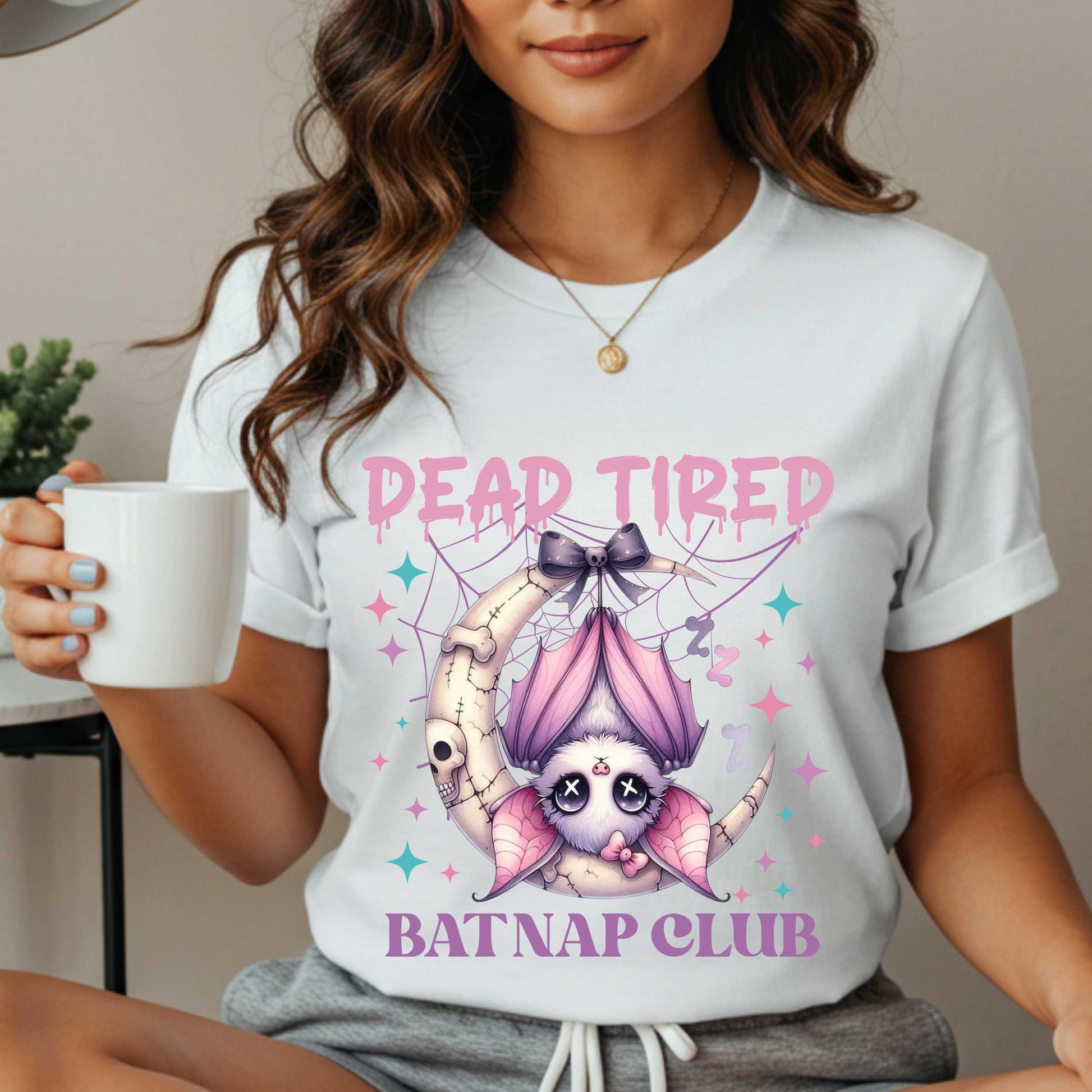 Dead tired and fully over it? Same. Join the Batnap Club with this pastel goth bat Halloween shirt, featuring a sleepy little winged gremlin who’s clearly clocked out. Wrapped in a pink bow and hanging like tomorrow’s problems, this adorable burnout bat is all of us in October (and every Monday). Perfect for spooky naps, haunted errands, or just surviving on caffeine and vibes.&nbsp;