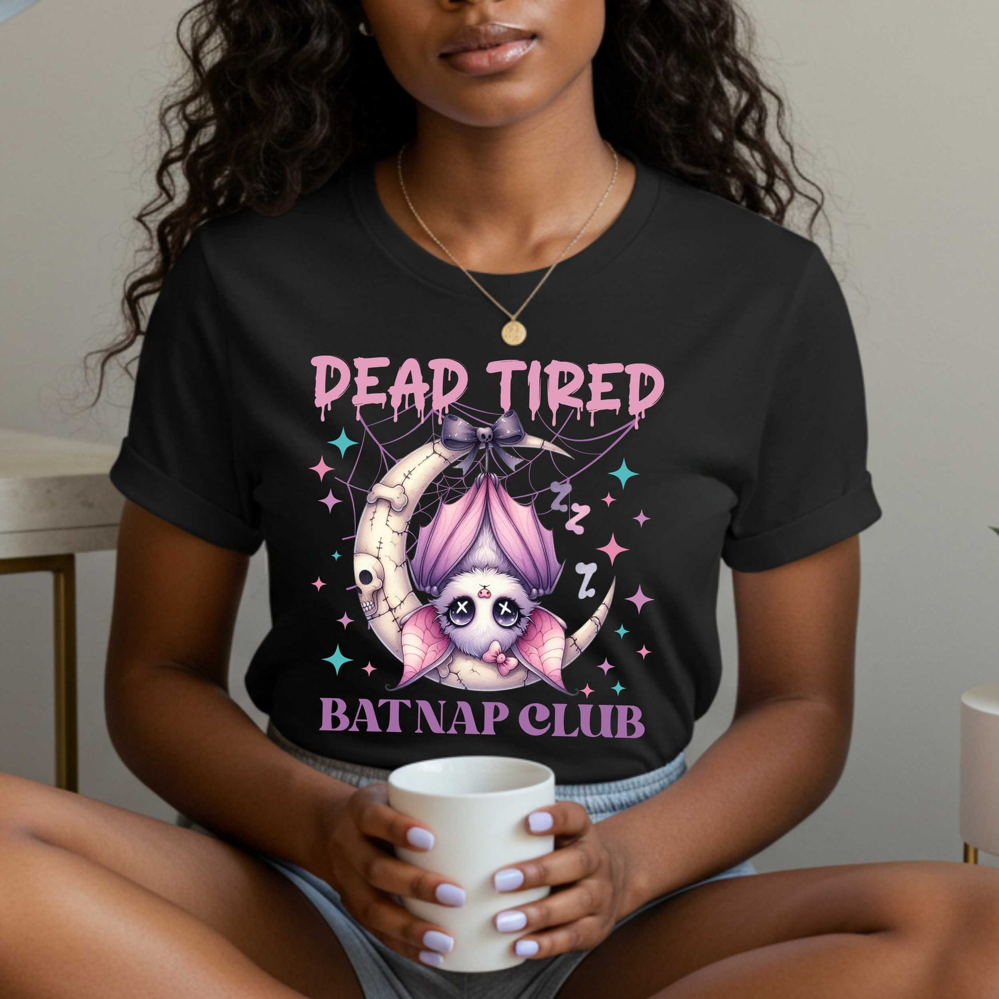 Dead tired and fully over it? Same. Join the Batnap Club with this pastel goth bat Halloween shirt, featuring a sleepy little winged gremlin who’s clearly clocked out. Wrapped in a pink bow and hanging like tomorrow’s problems, this adorable burnout bat is all of us in October (and every Monday). Perfect for spooky naps, haunted errands, or just surviving on caffeine and vibes.&nbsp;