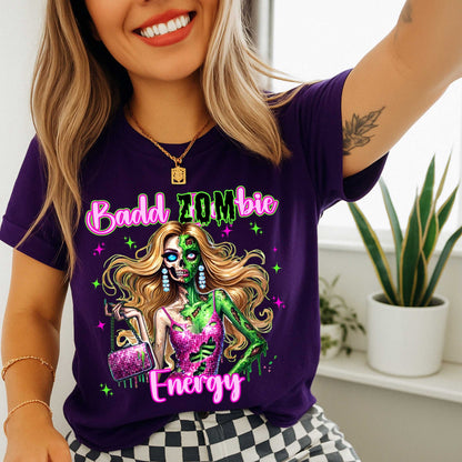 Brains, but make it fashion. This Badd Zombie Energy tee is for the girls who slay… even in the afterlife. Rocking a glittery pink dress, designer handbag, and enough undead glam to raise the dead, this zombie babe is dripping in sass (and maybe a little ooze).